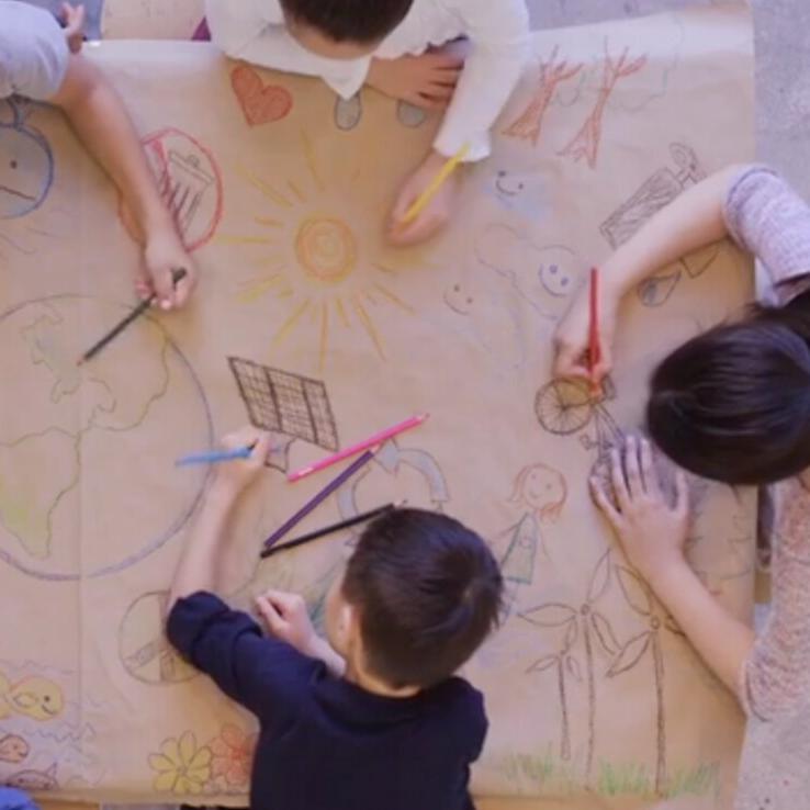 A group of students drawing on a large canvas together